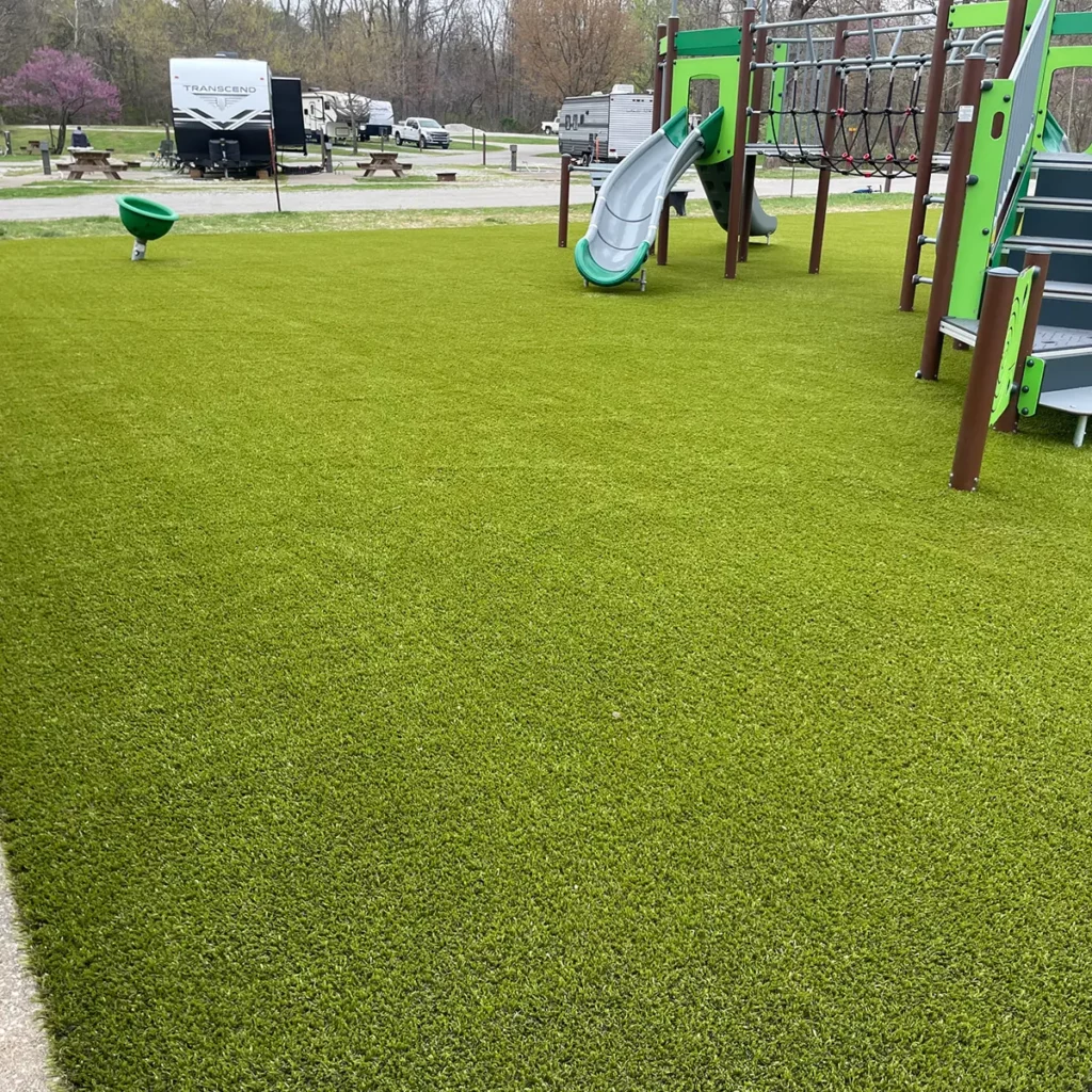 Lush artificial turf playground at RV campground with slide, climbing structure, and open play area on Playground Grass Ultra.