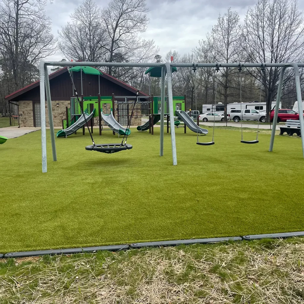 Artificial turf playground at RV campground with swing set, slides, and climbing structure on lush green Playground Grass Ultra.