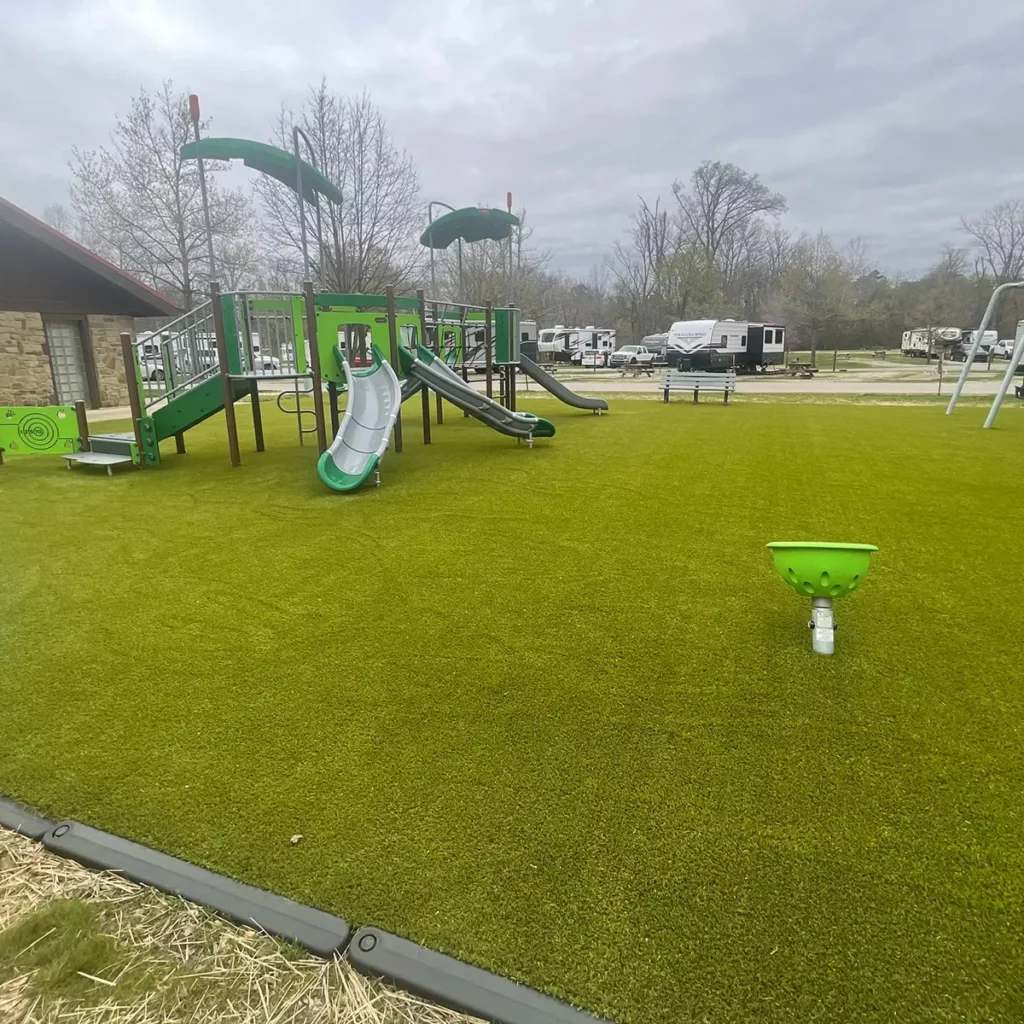 Lush artificial turf playground area at RV campground featuring green play structure with slides and spinners on Playground Grass Ultra.