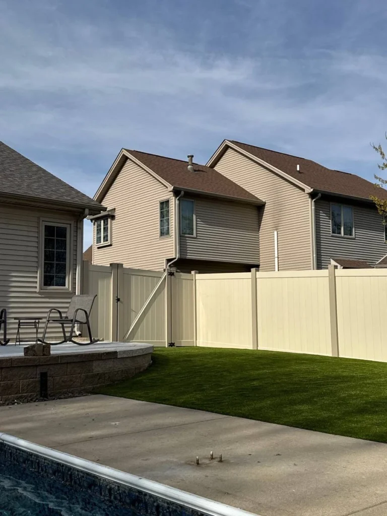 K9Grass artificial turf installed in fenced backyard beside pool and patio seating area of suburban home.
