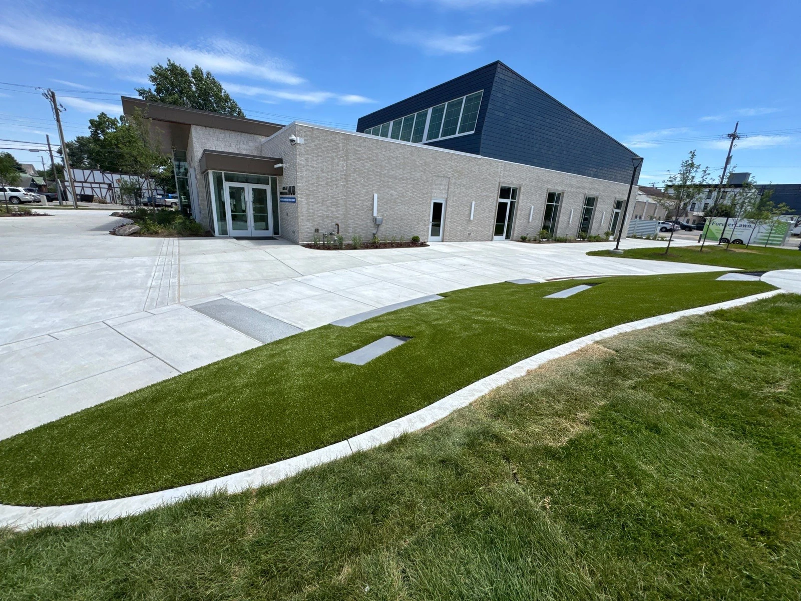ForeverLawn artificial turf installation at Batesville municipal building entrance with curved concrete edging and modern brick facade.