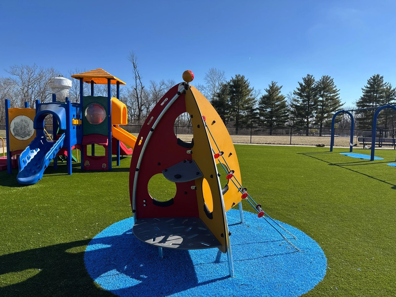 ForeverLawn Playground Grass installation at Clarks Creek Municipal Park in Plainfield with colorful climbing structures and blue safety zones.