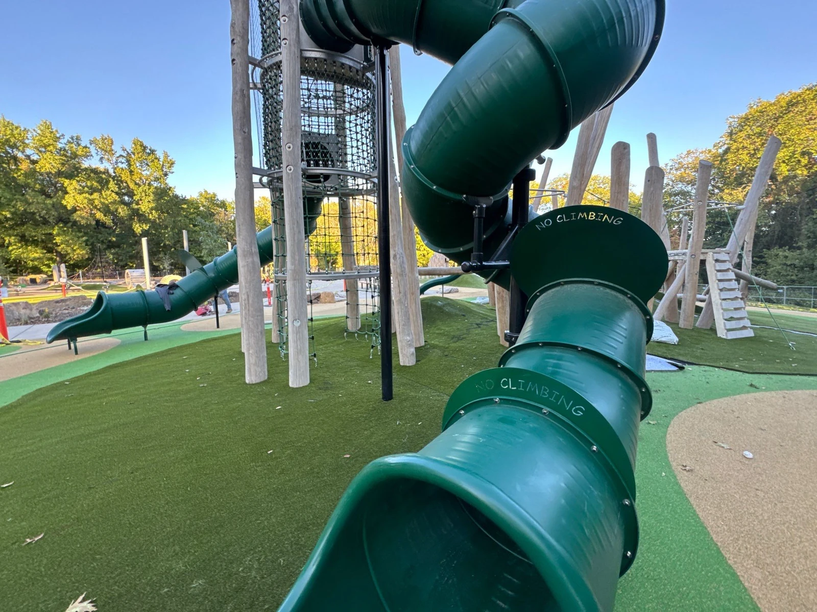 Green tube slides with NO CLIMBING labels over ForeverLawn Playground Grass Quest turf at Holliday Park Quest Playground, Indianapolis.
