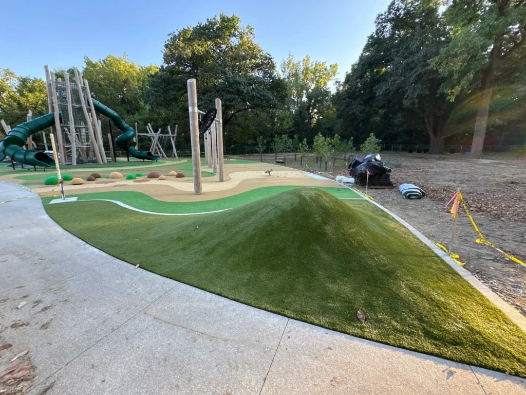 ForeverLawn Playground Grass Quest installation at Holliday Park with artificial turf mound, nature play equipment, and tube slides.