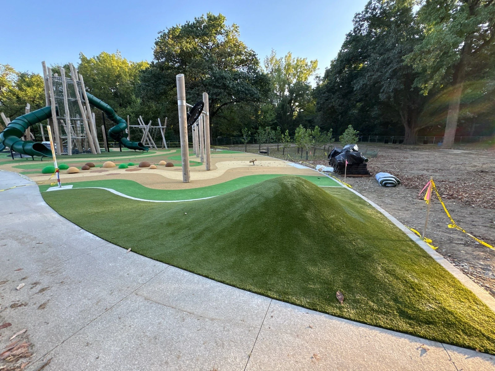 ForeverLawn Playground Grass Quest installation at Holliday Park with artificial turf mound, nature play equipment, and tube slides.