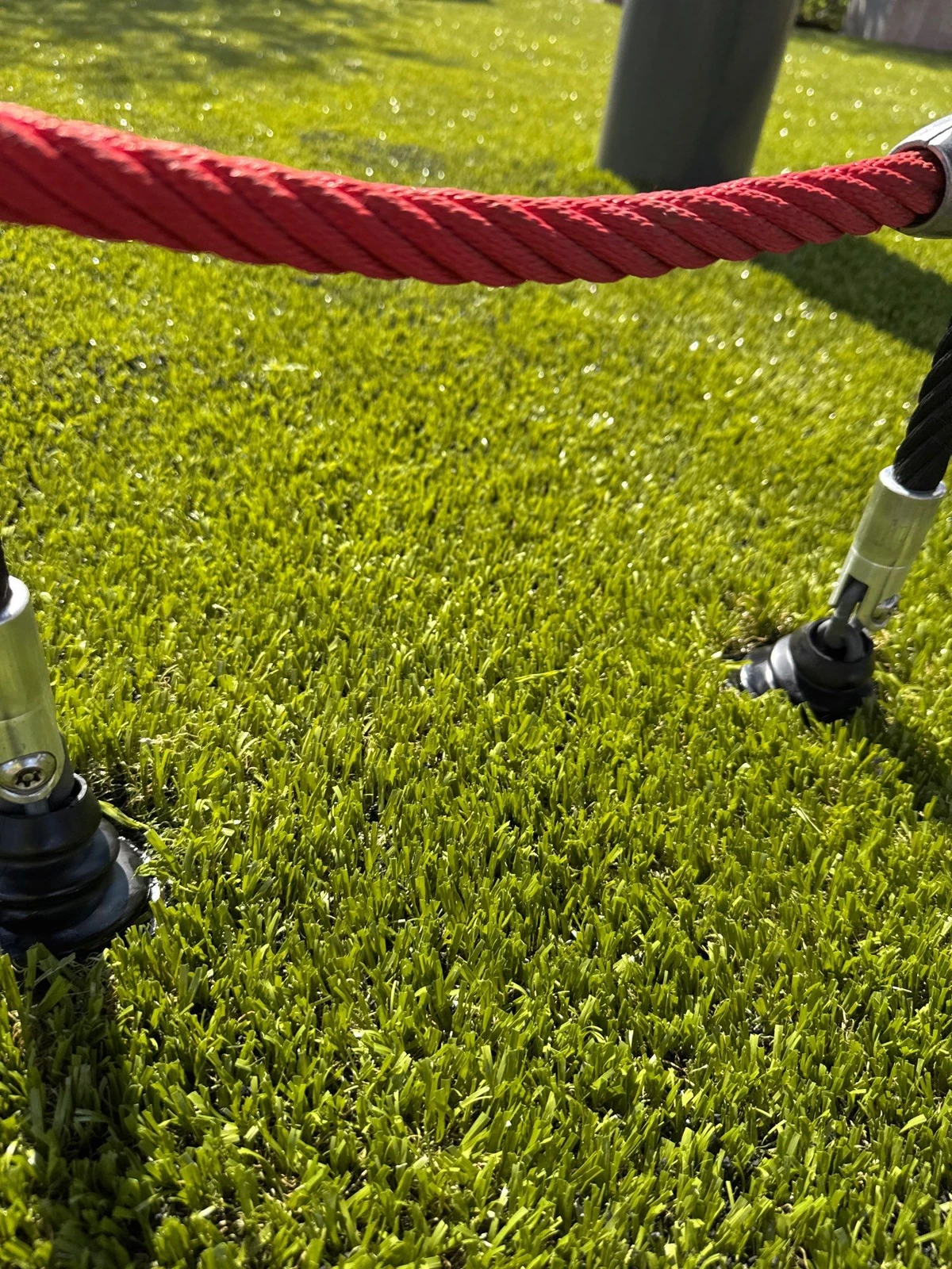 Red velvet rope stanchion on lush green K9Grass artificial pet turf installation at The Monon outdoor space.