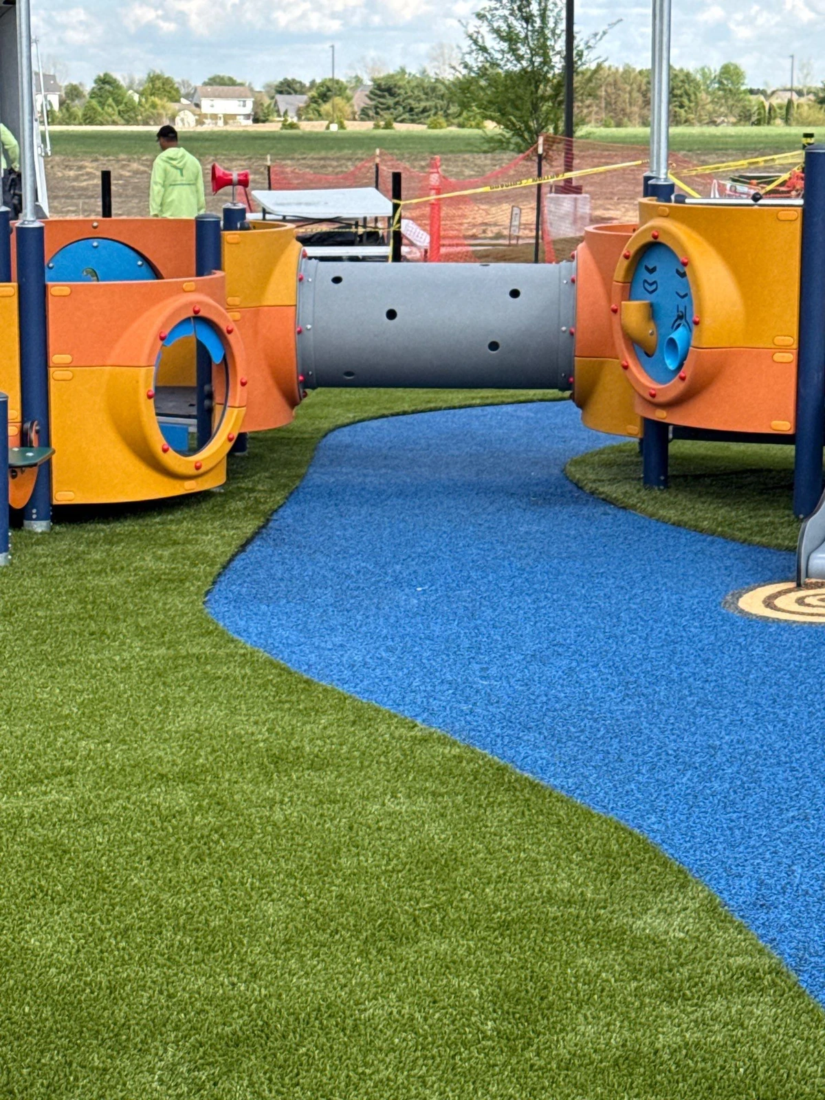 ForeverLawn Playground Grass installation with blue rubber path winding through colorful orange tunnel play structures at Mt. Vernon Park, Fortville IN.