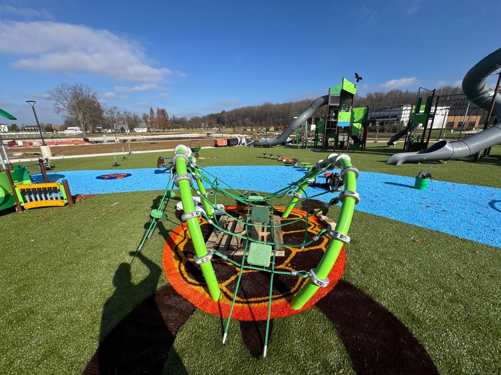 ForeverLawn Playground Grass installation at Ohio Township park featuring colorful turf patterns around climbing net structure with slides beyond.