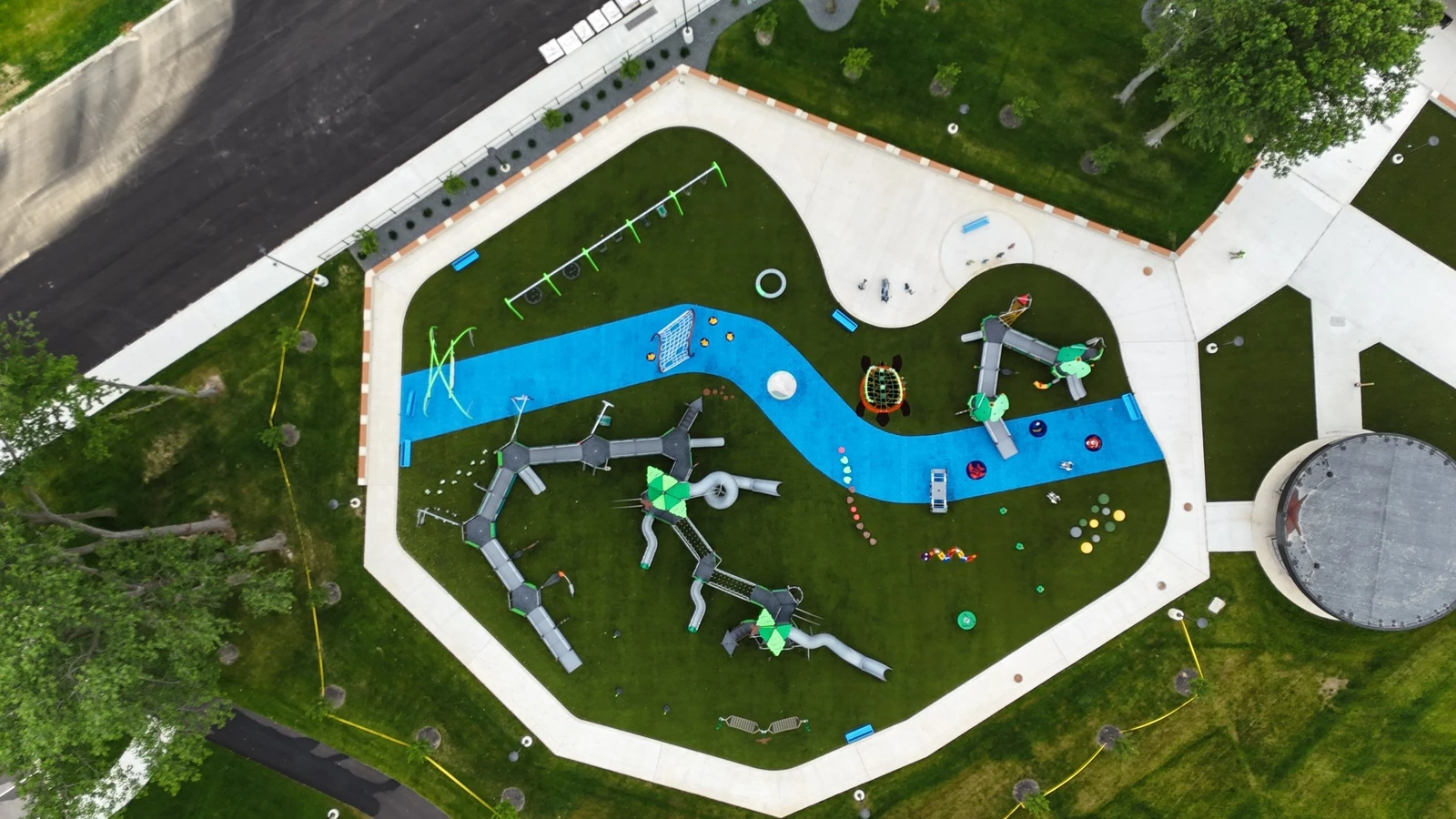 Aerial view of Ohio Township destination playground with synthetic turf, blue rubber pathways, and colorful play structures on artificial grass.