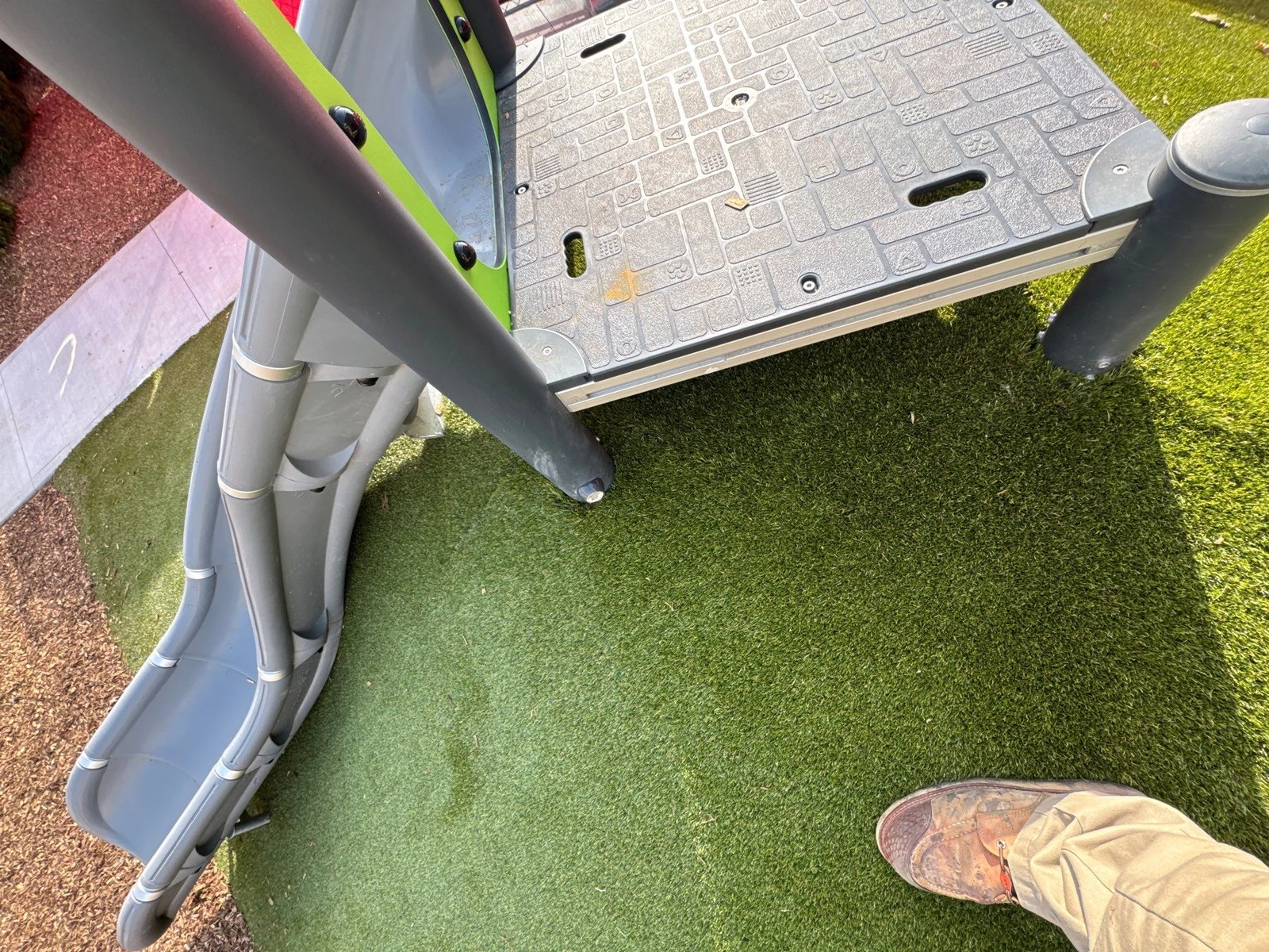 ForeverLawn Playground Grass installed around playground equipment base, artificial turf surface beside rubber safety surfacing, Indianapolis school.