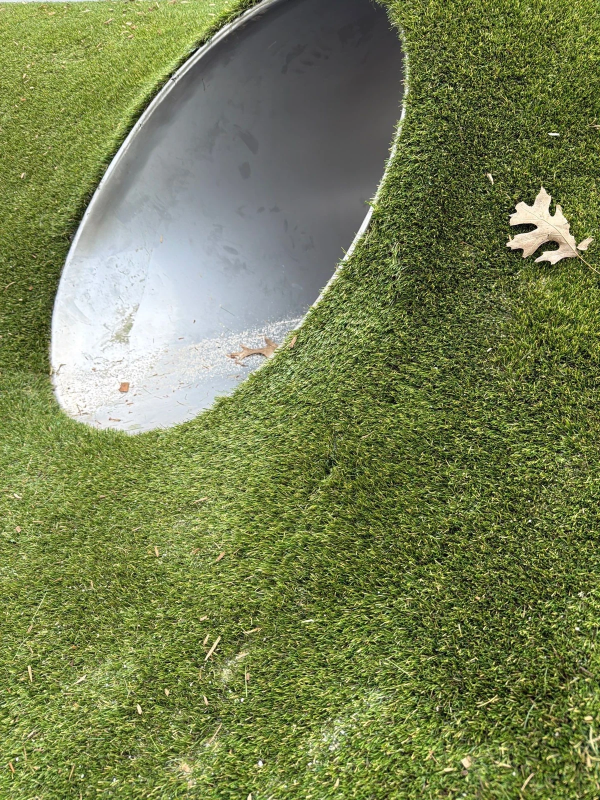 Artificial playground grass wrapped around a curved metal tunnel opening at St. Richards school Indianapolis.